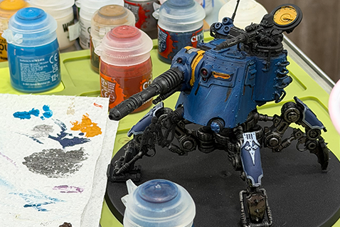 A painted miniature on a hobby table with Citadel paint pots